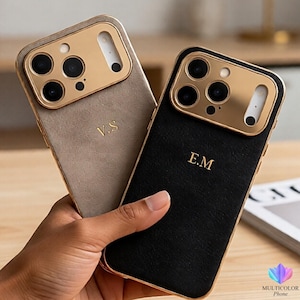 Peut inclure: Deux coques de téléphone avec des détails dorés et des initiales personnalisées. L'une est beige avec les initiales "V.S." et l'autre est noire avec les initiales "E.M." Les deux coques ont un aspect texturé et un cadre de caméra doré.