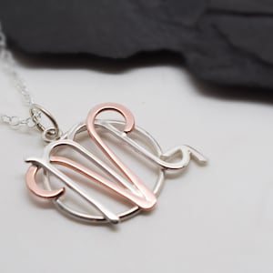 May include: A silver necklace with a rose gold Virgo zodiac sign pendant.