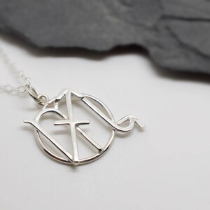 May include: Silver necklace with a pendant featuring a heart, cross, and a stylised letter 'M'.