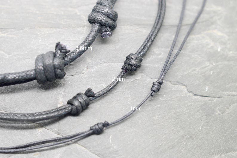 May include: Three black cords of different thicknesses, 1mm, 2mm, and 3.5mm, are shown knotted together. The cords are on a gray textured surface.