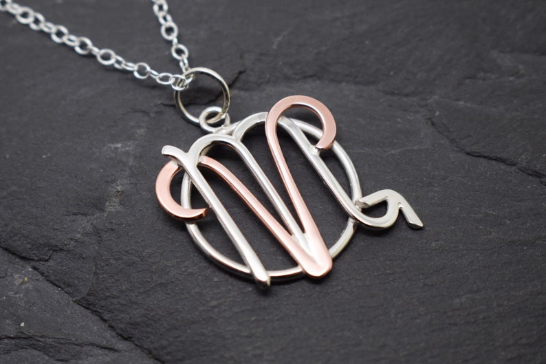 May include: Silver necklace with a rose gold Virgo zodiac sign pendant.