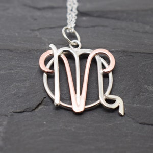 May include: A silver and rose gold necklace with a zodiac pendant featuring the symbol for Aries.