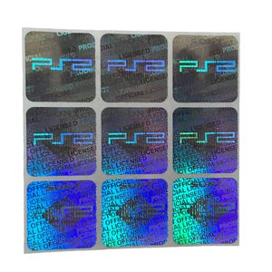 May include: A sheet of holographic stickers with the "PS2" logo in a blue gradient. Each square sticker with rounded corners has the text "LICENSED PRODUCT OFFICIAL". These stickers are designed for product authentication and security.