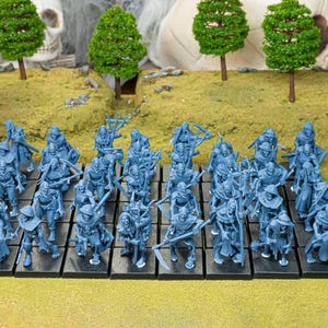May include: A collection of blue miniature figurines, likely for tabletop gaming, arranged on black bases. The figures depict skeletal warriors with various weapons and armor, set against a backdrop of miniature trees and a skull.