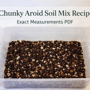 Può includere: Un contenitore di plastica trasparente riempito con un terriccio grossolano. Il terreno è una miscela di particelle marrone scuro, beige e bianche. Sopra il contenitore c'è un cartello bianco con il testo "Chunky Aroid Soil Mix Recipe Exact Measurements PDF."