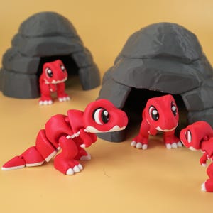 Puede incluir: Cuatro pequeñas figuras de dinosaurios rojos articuladas con detalles blancos en las garras y los ojos, cada una con un diseño de cuerpo segmentado. Dos de las figuras están colocadas frente a cuevas de roca gris oscuro en forma de cúpula.