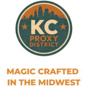 May include: Circular logo with a teal and orange color scheme. The logo features the text "KC PROXY DISTRICT" with a cityscape silhouette above the letters "KC" and two orange stars. Below the logo is the text "MAGIC CRAFTED IN THE MIDWEST."