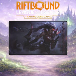 May include: A rectangular Riftbound League of Legends trading card game playmat. The mat features a detailed illustration of a character in a red and black outfit holding a mask and a large blade. The Riftbound and League of Legends logos are at the top.