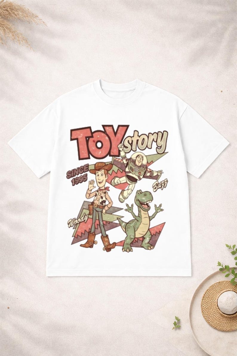 May include: White t-shirt featuring a retro-style graphic of Toy Story characters Woody, Buzz Lightyear, and Rex. The words "Toy Story" and "Since 1995" are also printed on the shirt. A fun, nostalgic design for fans of the animated film.