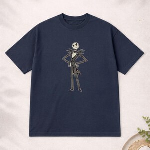 Puede incluir: Camiseta azul marino con un gr&aacute;fico de Jack Skellington de Pesadilla antes de Navidad. El personaje est&aacute; representado con su traje cl&aacute;sico con una cara blanca y un traje a rayas blanco y negro. La camiseta tiene mangas cortas y cuello redondo.