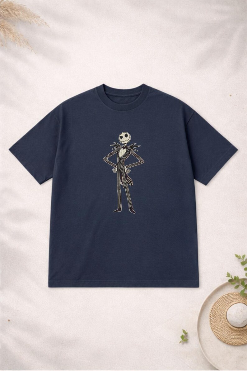 Puede incluir: Camiseta azul marino con un gr&aacute;fico de Jack Skellington de Pesadilla antes de Navidad. El personaje est&aacute; representado con su traje cl&aacute;sico con una cara blanca y un traje a rayas blanco y negro. La camiseta tiene mangas cortas y cuello redondo.