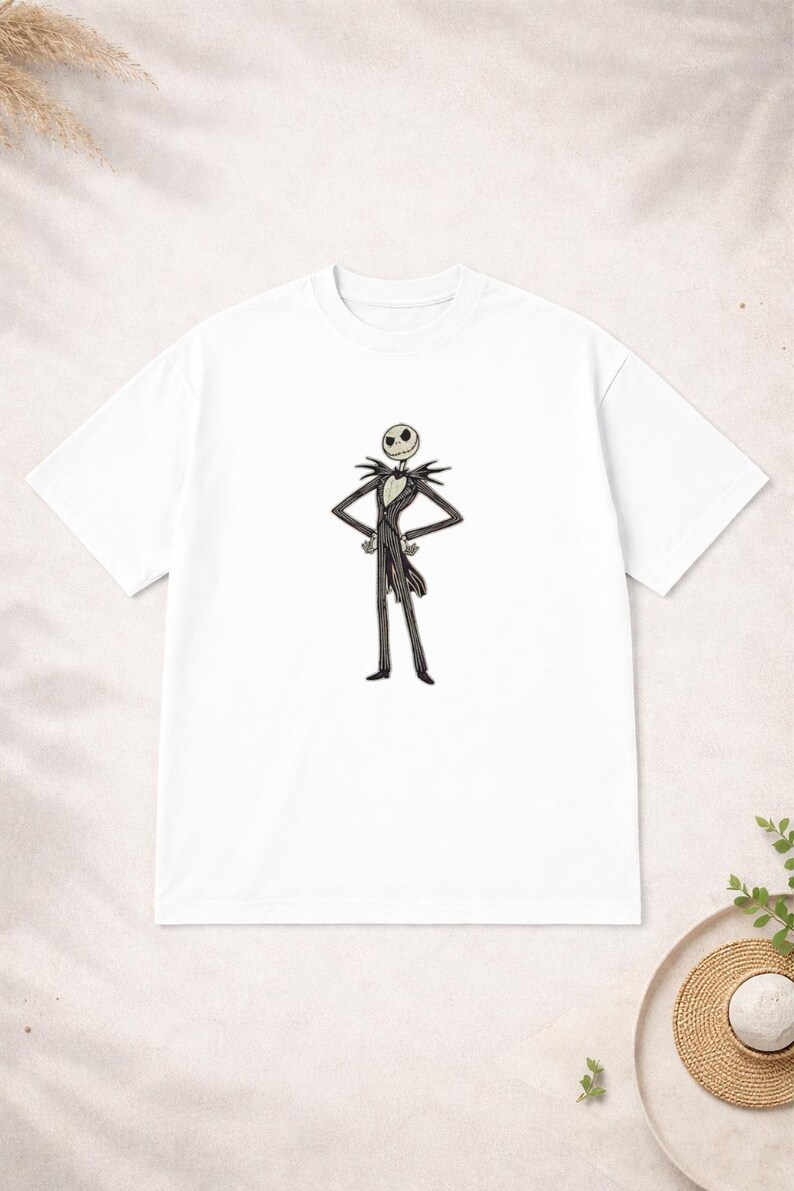 Puede incluir: Camiseta blanca con una ilustraci&oacute;n de Jack Skellington de Pesadilla antes de Navidad. El personaje est&aacute; representado con su traje blanco y negro, con los brazos cruzados. Un dise&ntilde;o cl&aacute;sico para los fans de la pel&iacute;cula.