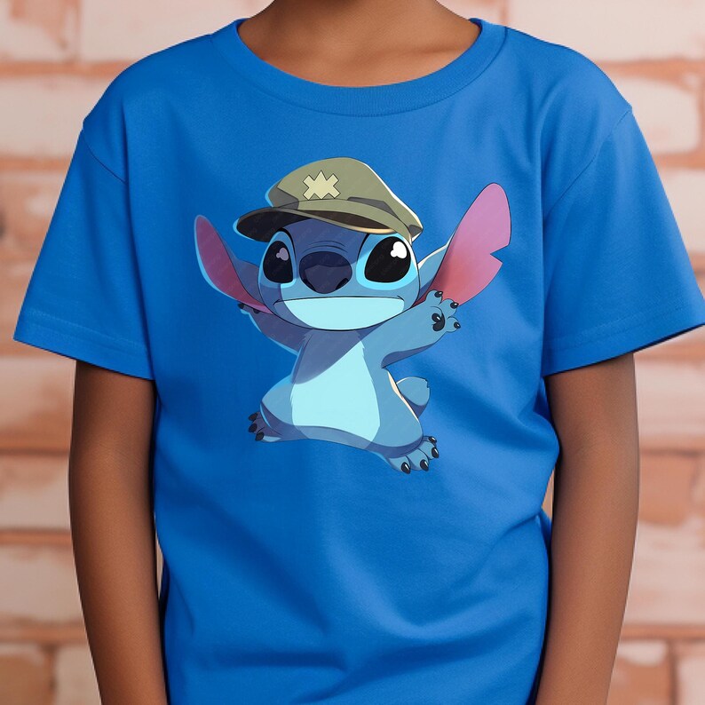 May include: A bright blue short-sleeved t-shirt featuring a graphic print of the blue alien character Stitch wearing a tan military-style cap with a cross emblem. The character is depicted with large ears, dark eyes, and a light blue chest patch.