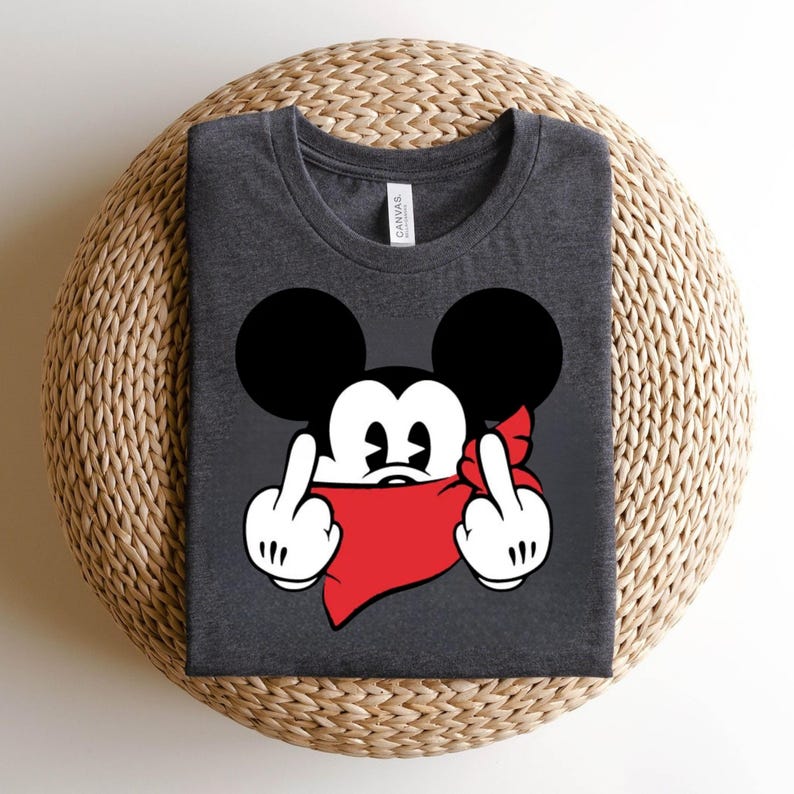 May include: Dark gray t-shirt featuring a cartoon mouse with black ears, white gloves, and a red bandana. The mouse is giving the middle finger with both hands. The shirt is made of a soft material.