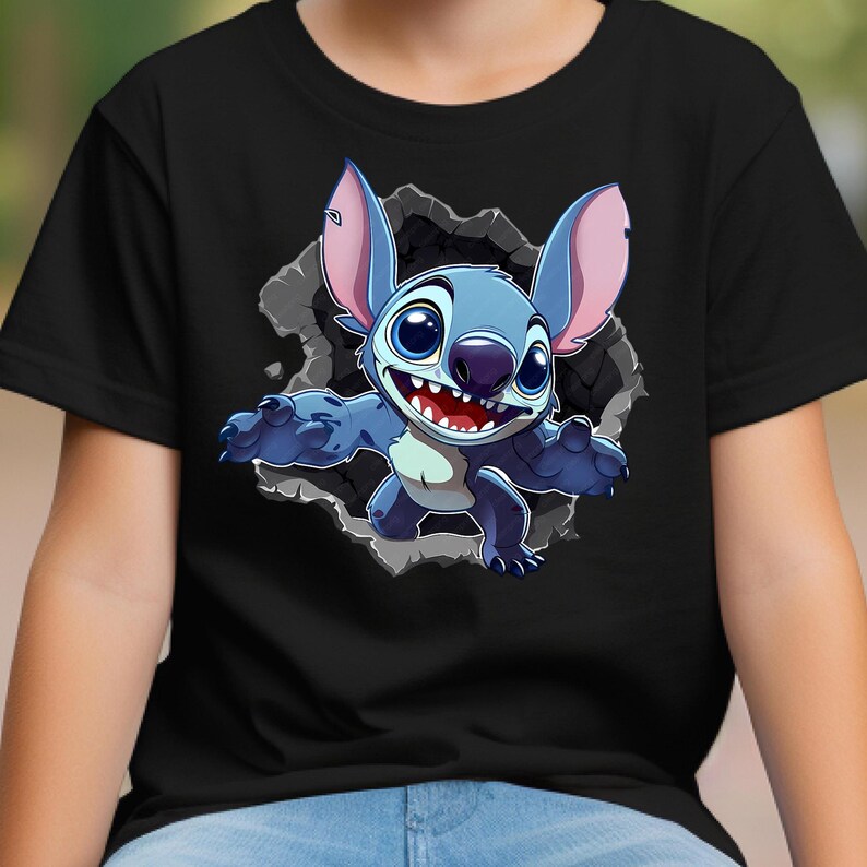 May include: Black t-shirt with a cartoon image of Stitch, a blue alien character, bursting from a grey, cracked wall. Stitch has big ears, a wide grin, and outstretched arms. The design is centrally placed on the shirt.