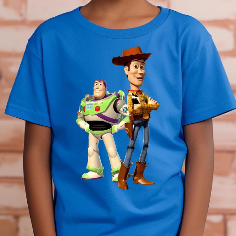May include: A bright blue short-sleeved t-shirt featuring a graphic print of the characters Buzz Lightyear and Woody from Toy Story. Buzz Lightyear is wearing a white, green, and purple space suit, while Woody wears a cowboy hat, yellow shirt, and vest.