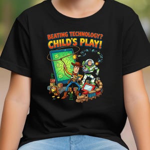 May include: Black t-shirt featuring a colorful graphic with the text "BEATING TECHNOLOGY? CHILD'S PLAY!". The design includes cartoon characters Woody and Buzz Lightyear, a tablet, and a toy train. The shirt is likely for children.