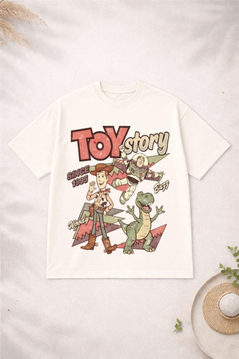 May include: White t-shirt featuring the words "Toy Story" in red and green, with Woody, Buzz Lightyear, and Rex graphics. The shirt also includes the text "Since 1995".