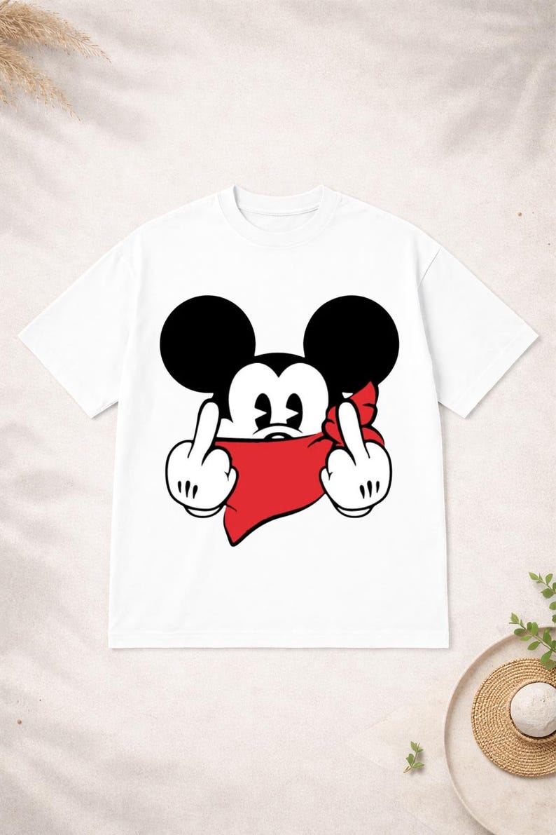 May include: White t-shirt featuring a cartoon mouse with black ears, a red bandana, and two fingers raised in a rude gesture. The mouse's face is visible, with a black nose and white eyes. The shirt is a casual, unisex style.