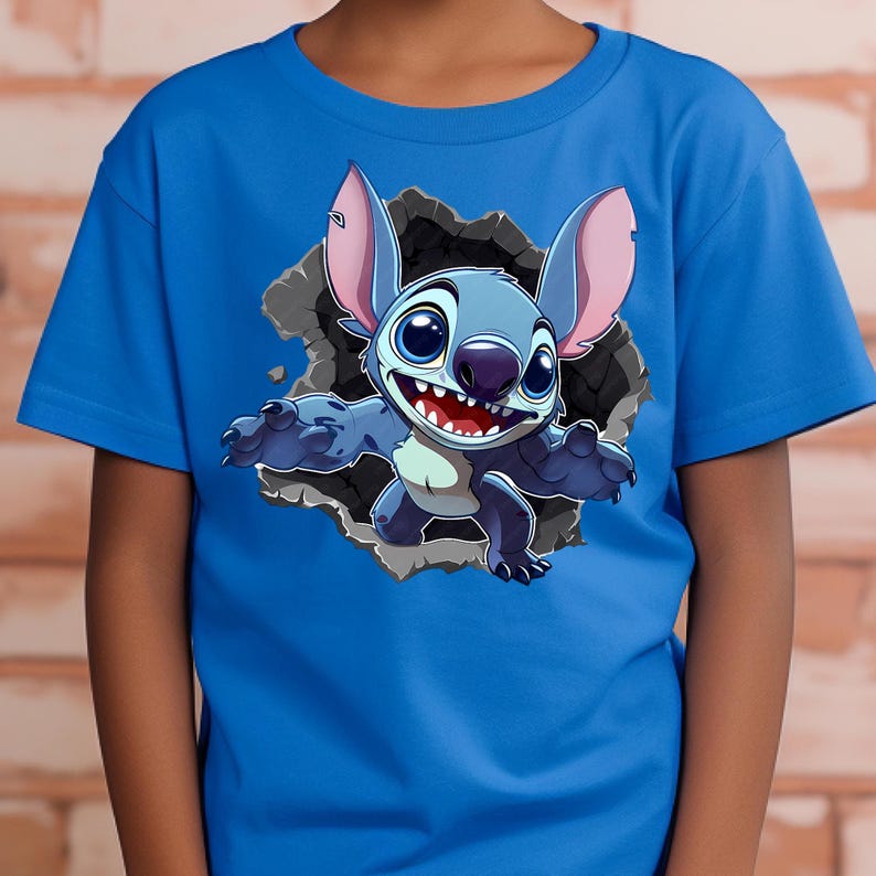 May include: A blue t-shirt with a cartoon image of Stitch from Lilo & Stitch. The character is breaking through a grey, cracked wall, smiling with open arms. The t-shirt is a solid blue colour.