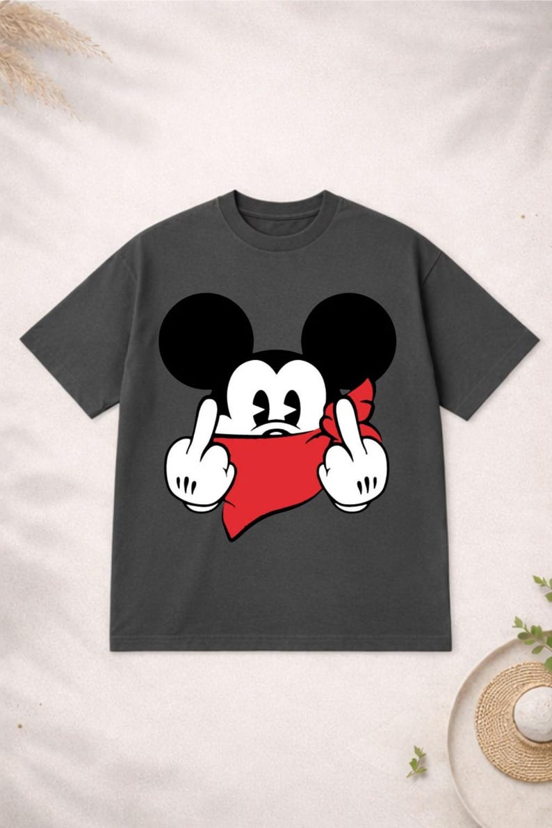 May include: Dark gray t-shirt featuring a cartoon character with large black ears and a red bandana. The character is giving the middle finger with both hands. A humorous and edgy graphic tee.