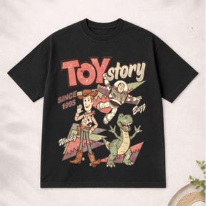 May include: Black t-shirt featuring a vintage-style graphic of characters from the movie "Toy Story." The design includes Woody, Buzz Lightyear, and Rex, with the text "TOY STORY SINCE 1995."