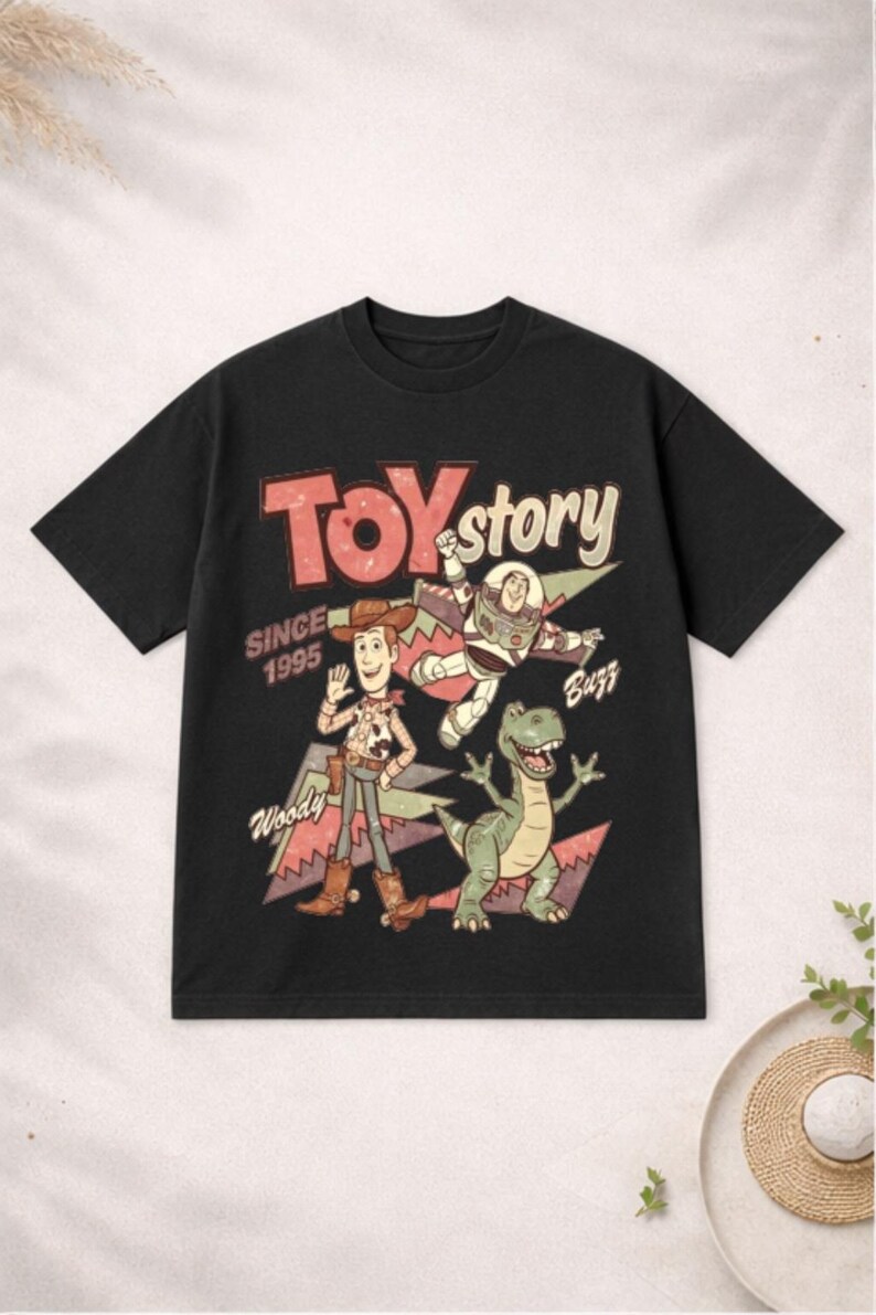 May include: Black t-shirt featuring a vintage-style graphic of characters from the movie "Toy Story." The design includes Woody, Buzz Lightyear, and Rex, with the text "TOY STORY SINCE 1995."