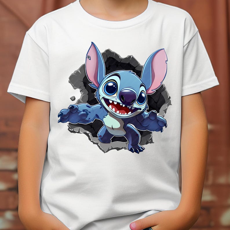 May include: White t-shirt with a cartoon illustration of Stitch, a blue alien character with large ears and a wide grin. The character is breaking through a gray, textured background. This is a children's apparel item.