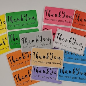 May include: A collection of rectangular stickers in various colors, including yellow, green, pink, and orange. Each sticker has the words "Thank You for your purchase!" in a handwritten-style font.