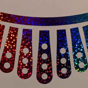 May include: A rainbow iridescent vinyl sticker with a design of a row of teardrop shapes with circles inside. The sticker is perfect for adding a touch of sparkle to any project.