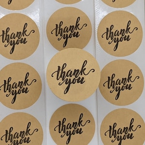 May include: A sheet of brown kraft paper stickers with the text "thank you" written in black cursive script.
