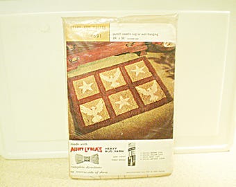 May include: A punch needle rug kit featuring a pattern of six squares with doves and stars. The kit includes heavy rug yarn, a punch needle, and instructions. The rug is 24 inches by 36 inches.