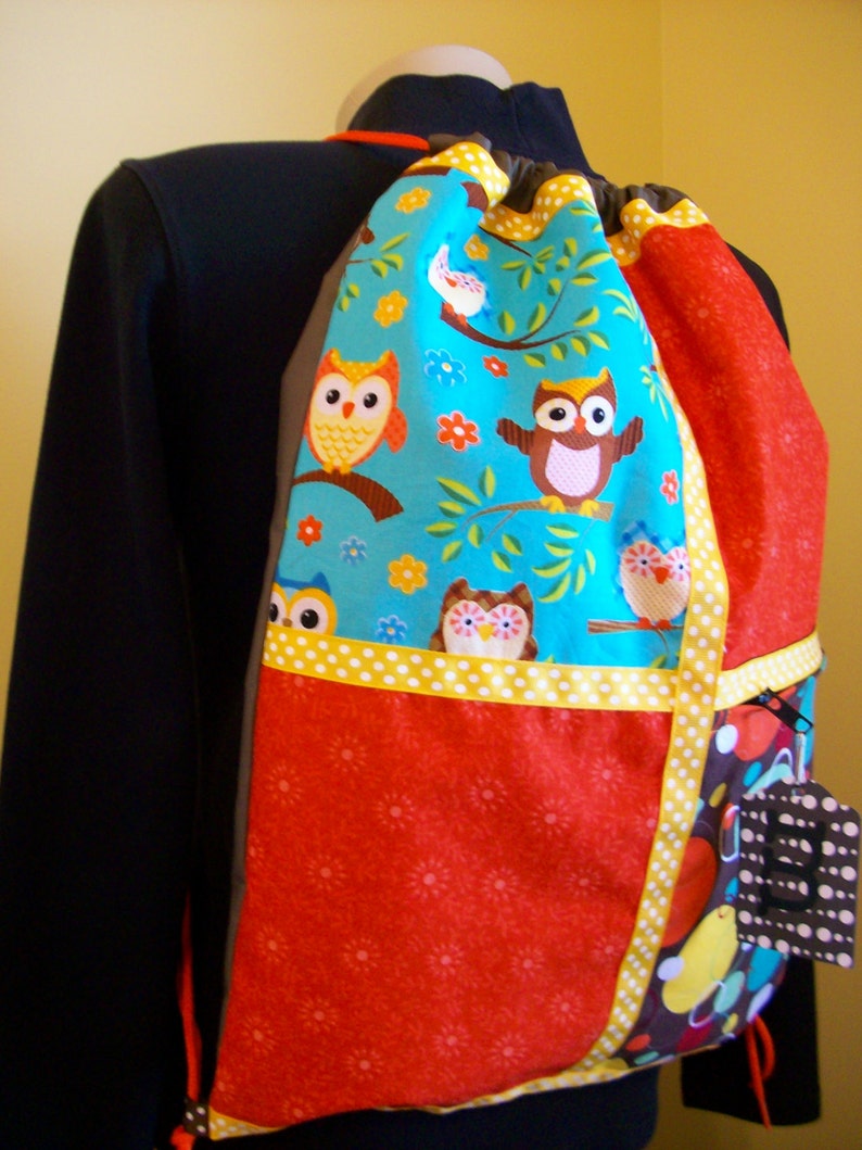 owls with orange and gold accents on a brown ripstop nylon drawstring backpack with front zipper pocket