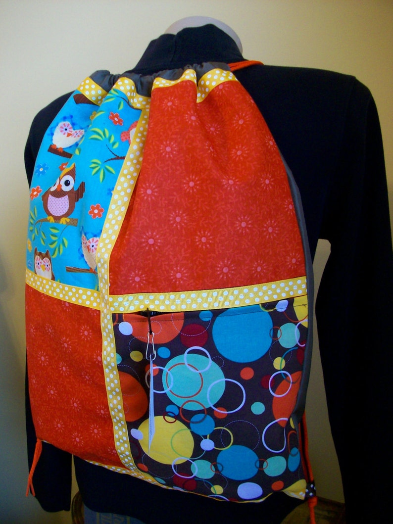 owls with orange and gold accents on a brown ripstop nylon drawstring backpack with front zipper pocket