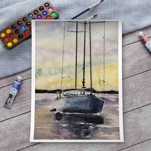 Könnte beinhalten: Aquarellmalerei eines Segelbootes auf dem Wasser. Das Boot ist ein gedämpftes Blau, mit hohen Masten und Takelage. Der Himmel ist eine Mischung aus Gelb-, Orange- und Lilatönen. Farbtuben, eine Holzpalette und Pinsel sind um das Gemälde angeordnet.