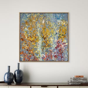 Könnte beinhalten: Abstrakter Kunstdruck mit einem Baum mit gelben, orangefarbenen und roten Herbstfarben vor einem hellblauen Hintergrund. Das Kunstwerk ist in einem Naturholzrahmen gerahmt. Dekorative Vasen befinden sich im Vordergrund.