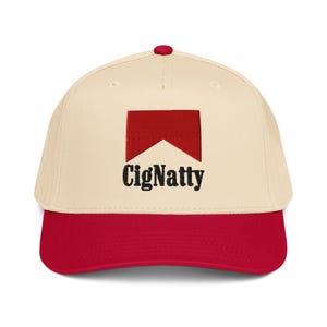 Könnte beinhalten: Cremefarbene Baseballkappe mit rotem Schirm und Knopf. Die Kappe hat ein rotes rechteckiges Logo mit einem weißen Chevron und dem Wort "CigNatty" in schwarzer, stilisierter Schrift.