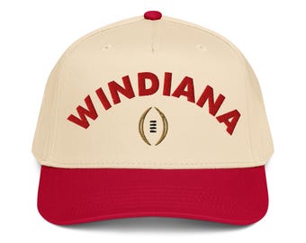 May include: A baseball cap with a cream-colored crown and a red brim. The word "WINDINANA" is embroidered in red across the front, above a gold football graphic. The cap has a red button on top.
