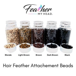 May include: Five clear plastic bottles filled with small, round, hair feather attachment beads in five different colors: blonde, light brown, brown, dark brown, and black. The bottles are labeled with the color of the beads. The text "Feather MY HEAD." is at the top of the image. The text "Hair Feather Attachement Beads" is at the bottom of the image.