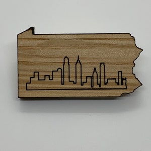 May include: A wooden cutout of the state of Pennsylvania with a black silhouette of the Philadelphia skyline.