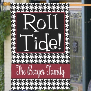 May include: A rectangular outdoor flag with a black and white houndstooth pattern border. The center features the words "Roll Tide!" in white on a black background, with "The Berger Family" below in white on a burgundy stripe.