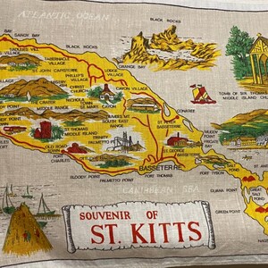 May include: A beige souvenir map of St. Kitts, featuring a yellow outline of the island with various landmarks and place names. The map includes the text "Souvenir of St. Kitts" in a scroll.