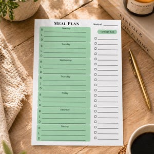 May include: A white meal plan sheet with green accents, featuring sections for each day of the week and a grocery list. The text "MEAL PLAN" is at the top. A gold pen, a candle, and a cup of coffee are also visible.