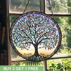 May include: A round stained glass window featuring a tree design with colorful leaves. The tree has a dark brown trunk and branches, with leaves in shades of red, yellow, blue, and green. The window is framed in a dark metal and hangs from a chain. Text at the bottom reads "BUY 2 GET 1 FREE".