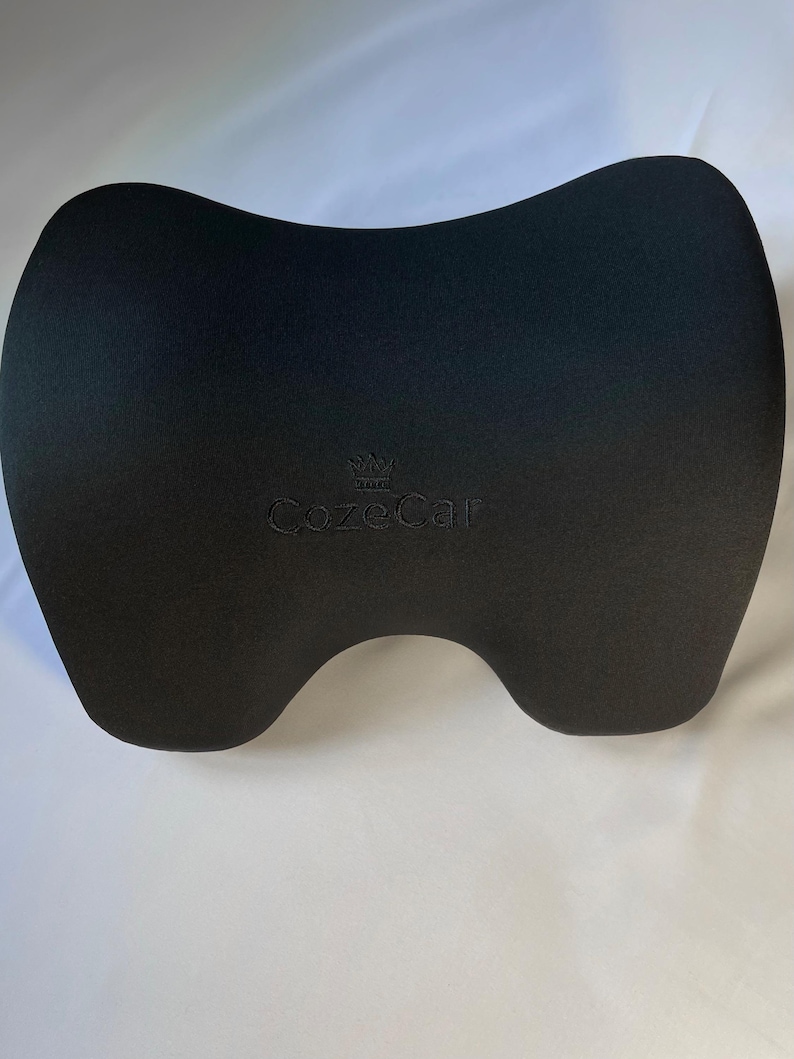 Pode incluir: Um apoio de cabe&ccedil;a preto para carro com formato contornado para suporte do pesco&ccedil;o. O apoio de cabe&ccedil;a tem um acabamento liso e fosco e apresenta o texto bordado "CozeCar" em um tom de preto mais claro.