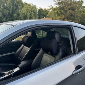 Pode incluir: Um carro coup&eacute; prateado com interior em couro preto. Os bancos dianteiros s&atilde;o vis&iacute;veis, com encostos de cabe&ccedil;a e apoios de bra&ccedil;os. O carro est&aacute; estacionado ao ar livre com &aacute;rvores ao fundo.