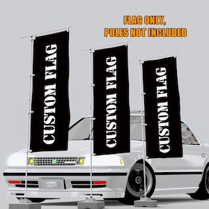 Può includere: Tre bandiere rettangolari nere con la scritta "CUSTOM FLAG" in bianco sono esposte davanti a un'auto bianca. Le bandiere sono montate su pali bianchi. Il testo "FLAG ONLY, POLES NOT INCLUDED" è in alto.
