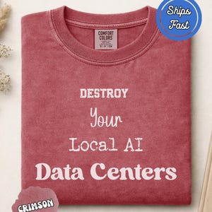 Puede incluir: Una camiseta de cuello redondo color carmesí con textura desgastada. La prenda presenta un texto blanco impreso en el frente que dice: DESTROY Your Local AI Data Centers. La etiqueta interior del cuello muestra el logo Comfort Colors y la talla S-P-CH.