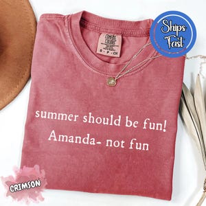 Könnte beinhalten: Karmesinrotes T-Shirt mit dem weißen Text "summer should be fun! Amanda- not fun". Das Shirt hat einen Rundhalsausschnitt und ein kleines Etikett. Eine silberne Halskette mit Anhänger liegt auf dem Shirt.