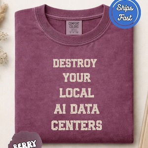 Puede incluir: Una camiseta de cuello redondo color baya con el texto "DESTROY YOUR LOCAL AI DATA CENTERS" en una tipografía desgastada de color blanco roto. La prenda incluye una etiqueta de la marca Comfort Colors y una insignia azul "Ships Fast".